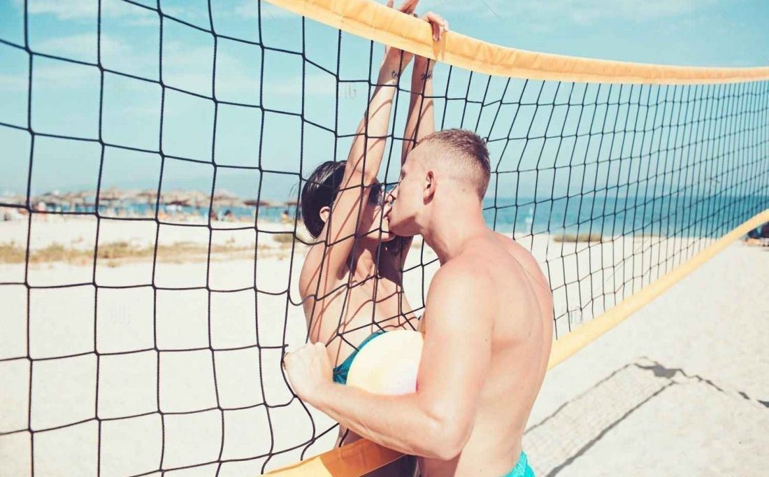 couple kissing while playing volleyball